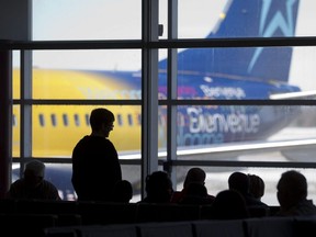 Travellers wait in the departure lounge at London International Airport to board a Transat Holidays flight to Cuba in London, Ont. March 12, 2015.