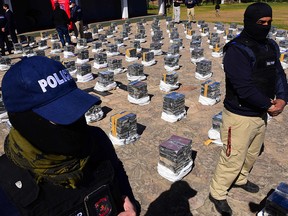 Police stand guard over seized packages of cocaine displayed to the press at the Special Forces Police headquarters in Asuncion, on July 28, 2021.