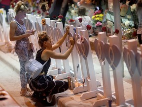 People visit the memorial that has pictures of some of the victims from the partially collapsed 12-story Champlain Towers South condo building on July 15, 2021 in Surfside, Florida.