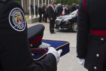 A police officer holds the cap of Toronto Police Const. Jeffrey Northrup as a hearse bearing his casket arrives for his funeral  in Toronto on Monday, July 12, 2021.