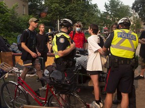 An encampment supporter is detained by the police as city officials work to clear the Alexandra Park encampment in Toronto on Tuesday, July 20, 2021.