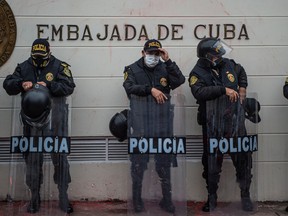 Police officers stand guard outside the Cuban Embassy during a demonstration of Cuban citizens residing in Peru against Cuban government of President Miguel Diaz-Canel in Lima, on July 13, 2021.