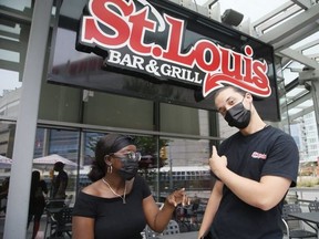 Servers Anta Owusu (left) and Griffin Rowe are pictured in front of the St. Louis Bar and Grill on July 18, 2021.