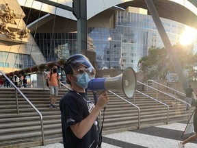 A City of Toronto worker uses a bullhorn to encourage Blue Jays fans to stop into a pop-up clinic to get vaccinated before heading into the Rogers Centre on Friday, July 30, 2021.