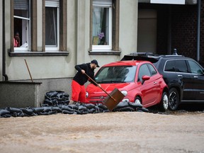 A man sets up sand bags next to damaged cars in a flooded street on July 14, 2021 in Hagen, western Germany.