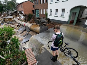 A cyclist takes pictures of an area completely destroyed by the floods in the Blessem district of Erftstadt, western Germany, on July 16, 2021.