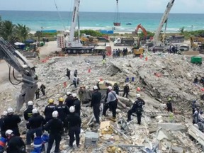 Search-and-rescue personnel work on the debris of the collapsed Champlain Towers South condominium in Surfside, Fla., Monday, July 5, 2021, in this still image obtained from video.