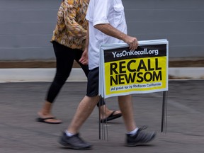Supporters of the recall campaign of California governor Gavin Newsom leave with yard signs after attending an information session and rally in Carlsbad, California, June 30, 2021.