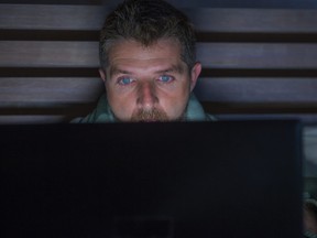 young attractive and relaxed internet addict man networking concentrated late at night on bed with laptop computer in social media addiction or workaholic businessman concept