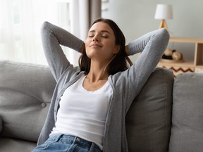 Relaxed serene young woman lounge on comfortable sofa at home