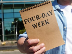 Man proposes four-day week sign. Notepad in hand.