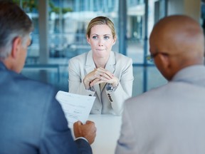 Tensed business woman sitting in front of panel of interviewers