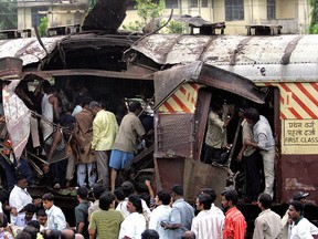 Mumbai, INDIA: (FILES) In this file photo taken, 11 July 2006, Rescue workers search for bodies inside the mangled compartment of one of the blast affected local trains at Mahim railway station in Mumbai.