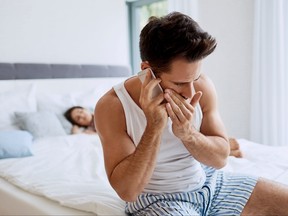 Handsome young man cheating on girlfriend talking with lover while she is sleeping in the background