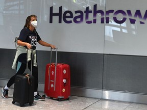 In this file photo taken on July 10, 2020 passengers wearing a mask arrive at Heathrow airport, west London, on July 10, 2020.