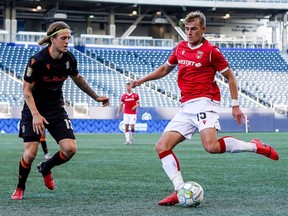 Forge FC midfielder Alexander Achinioti-Jonsson challenges Elliot Simmons of Cavalry FC in a CPL game at Investors Group Field in Winnipeg bubble 8, 2021.