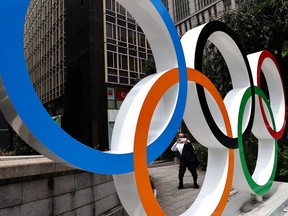 A man wearing a protective mask, amid the COVID-19 pandemic, takes a photo of an Olympic Ring installation in Tokyo, Japan, July 28, 2021.