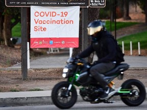 A motorcyclist rides past a COVID-19 vaccine site in Los Angeles, Tuesday, July 6, 2021.