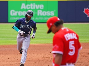 Shed Long Jr. of the Seattle Mariners runs the bases after hitting a two-run home run during the third inning as Santiago Espinal of the Blue Jays looks down at Sahlen Field on July 1, 2021 in Buffalo.