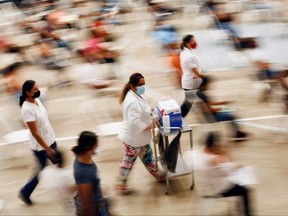 Claudia Gutierrez, a health worker, walks with doses of the Pfizer-BioNTech COVID-19 vaccine during a mass vaccination program for people over 18 years of age at a gym in Praxedis G. Guerrero, Mexico July 10, 2021.