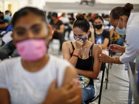 A woman receives a dose of the Pfizer-BioNTech COVID-19 vaccine, during a mass vaccination program for people over 18 years of age at a gym in Guadalupe Mexico, July 10, 2021.