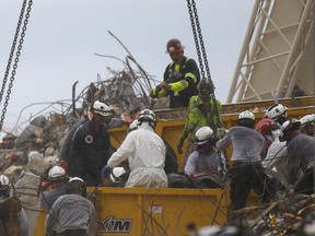 Rescue personnel carry a stretcher as they continue the search and rescue operation for survivors at the site of a partially collapsed residential building in Surfside, near Miami Beach, Florida, June 30, 2021.