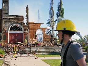 Firefighter Graham Glaubitz walks past St. Jean Baptiste Parish in Morinville, Alberta, which was burned to the ground on Wednesday June 30, 2021. Police are investigating the suspicious fire at the historic Catholic church.