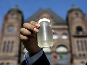 Kiiwetinoong MPP Sol Mamakwa holds up water collected from Neskantaga First Nation, where residents were evacuated over tainted water last month, during a rally at Queen's Park in Toronto on Friday, Nov. 6, 2020.