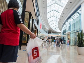 A child holds a shopping bag as he waits in line in Sherway Gardens mall in Toronto, June 30, 2021.