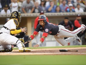 Starlin Castro of the Washington Nationals dives trying to score against Victor Caratini of the San Diego Padres in the second inning at Petco Park on July 6, 2021 in San Diego, Calif.