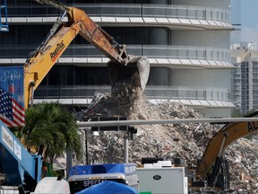 Construction equipment is used to dig through the mound of debris from the collapsed 12-story Champlain Towers South condo building is seen through fencing on July 11, 2021 in Surfside, Fla.