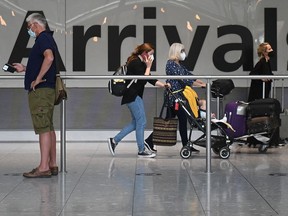 In this file photo taken on June 3, 2021 passengers push their luggage on arrival in Terminal 5 at Heathrow airport in London.