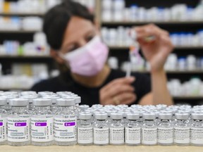 Barbara Violo, pharmacist and owner of The Junction Chemist Pharmacy, draws up a dose behind vials of both Pfizer-BioNTech and Oxford-AstraZeneca COVID-19 vaccines on the counter, in Toronto, Friday, June 18, 2021.