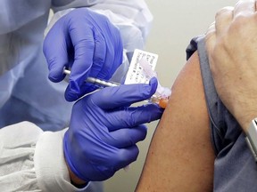 A subject receives a shot in the first-stage safety study clinical trial of a potential vaccine by Moderna for COVID-19 at the Kaiser Permanente Washington Health Research Institute in Seattle, March 16, 2020.