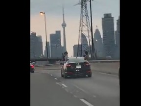 Two young men are seen hanging out the windows of a car on the Gardiner Expressway in video reportedly shot on Monday, July 5, 2021.