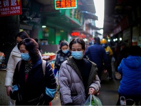 People wearing face masks walk on a street market, following an outbreak of the coronavirus disease (COVID-19) in Wuhan, Hubei province, China February 8, 2021.