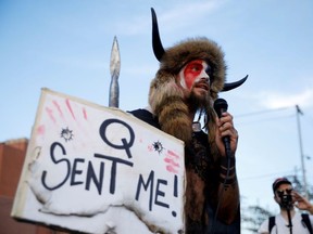 Jacob Chansley, holding a sign referencing QAnon, speaks as supporters of U.S. President Donald Trump gather to protest about the early results of the 2020 presidential election, in front of the Maricopa County Tabulation and Election Center (MCTEC), in Phoenix, Arizona November 5, 2020.