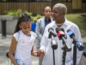 Tenesha Wilson, the aunt of homicide victim Chavaughn Jones, is joined by her nephew's daughter as she addresses media at 1 Vendome Pl. in Flemingdon Park area in Toronto, Ont., on Saturday, July 3, 2021.
