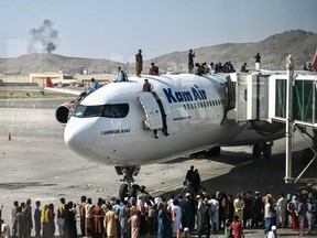 Afghanis climb atop a plane the Kabul airport on August 16, 2021.