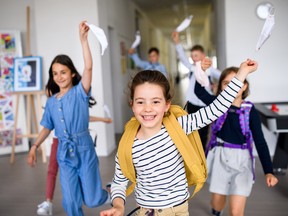 Group of cheerful children going home from school after covid-19 quarantine and lockdown, taking off face masks.