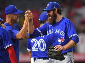 Blue Jays closer Jordan Romano celebrates with pitching coach Pete Walker after beating the Angles on Tuesday night.