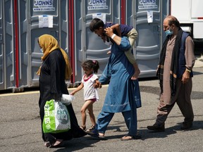 An Afghan man carries a boy on his shoulders upon arrival at a processing centre for refugees evacuated from Afghanistan at the Dulles Expo Center near Dulles International Airport in Chantilly, Va., on Aug. 24, 2021.