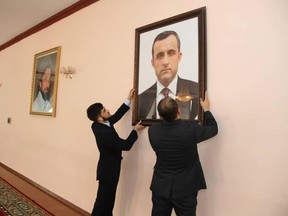 Afghan embassy staff hang a portrait of Afghan First Vice President Amrullah Saleh, who declared himself the "legitimate caretaker president," on the wall at the embassy in Dushanbe, Tajikistan, in this picture released August 18, 2021.