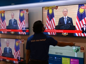 A man watches a television on display at a shopping mall store as Malaysian Prime Minister Muhyiddin Yassin announces his resignation as he addresses the nation during a live telecast in Kuala Lumpur on August 16, 2021.