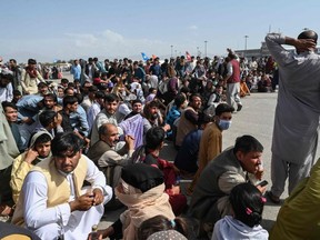 Afghan passengers sit as they wait to leave Kabul airport on August 16, 2021.