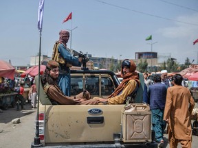 Armed Taliban fighters on a pickup truck move around a market area flocked with local Afghan people at the Kote Sangi area of Kabul on August 17, 2021, after Taliban seized control of the capital following the collapse of the Afghan government.