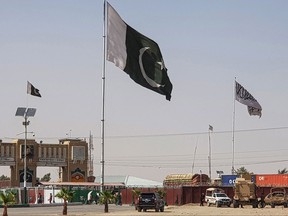 Pakistani flags (C) and Taliban flag (R) flutter on their respective border sides as seen from the Pakistan-Afghanistan border crossing point in Chaman on August 18, 2021.