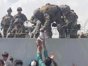 This image taken by Omar Kaidiri and made available to AFP on August 20 shows a US Marine grabbing an infant over a fence of barbed wire during an evacuation at Hamid Karzai International Airport in Kabul on August 19, 2021.