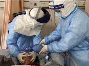 In this file photo taken on Feb. 16, 2020 shows medical staff members treating a patient infected by COVID-19 at the Wuhan Red Cross Hospital in Wuhan in China's central Hubei province.