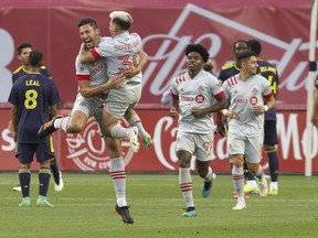 Toronto FC's Omar Gonzalez (centre left) celebrates with Yeferson Soteldo after scoring the game's opening goal during first half MLS    action against Nashville SC, in Toronto on Sunday, August 1, 2021.